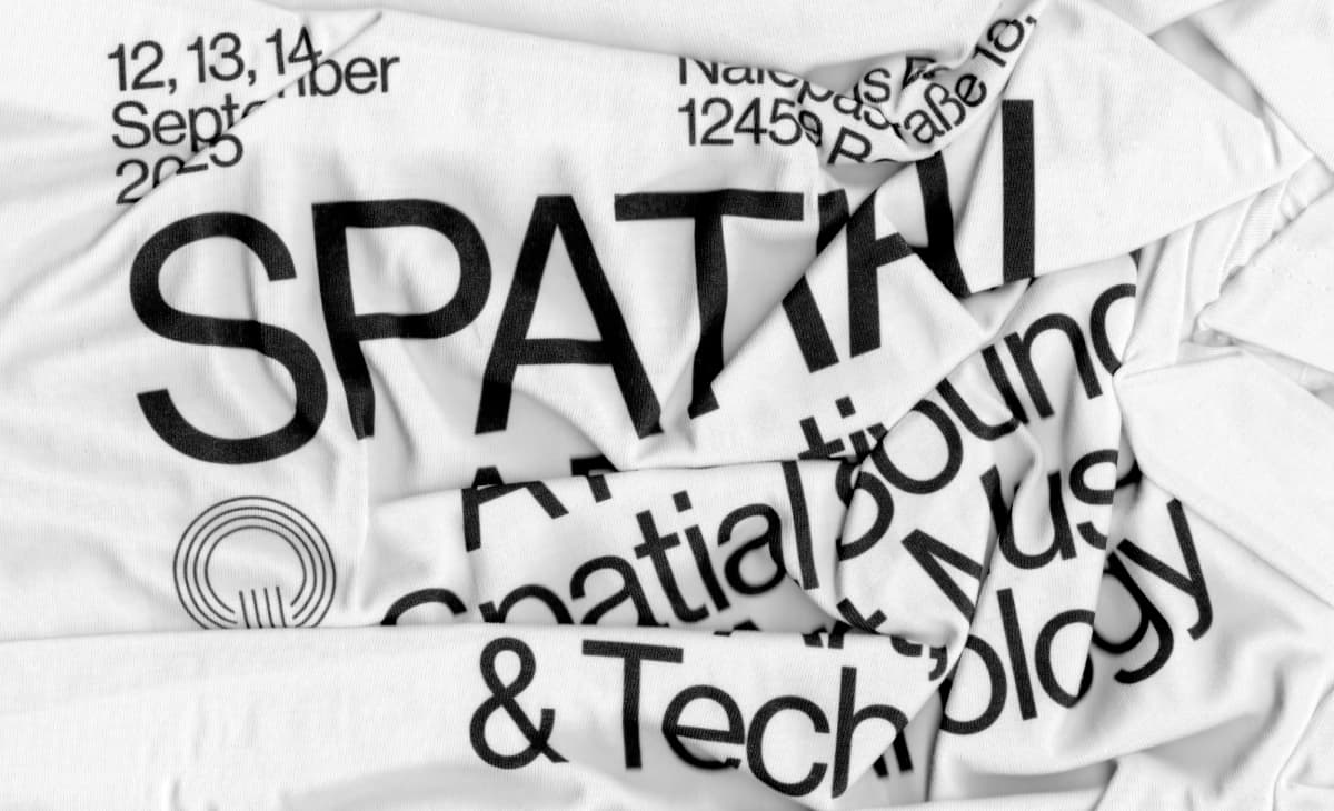 Black Spatial lettering across folded white festival T-shirts